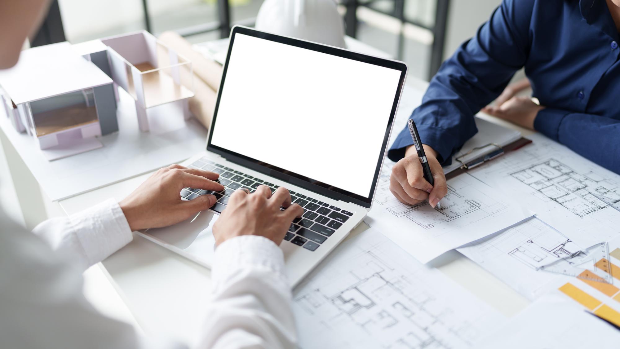 consultare în birou cu laptop și planuri pe masă